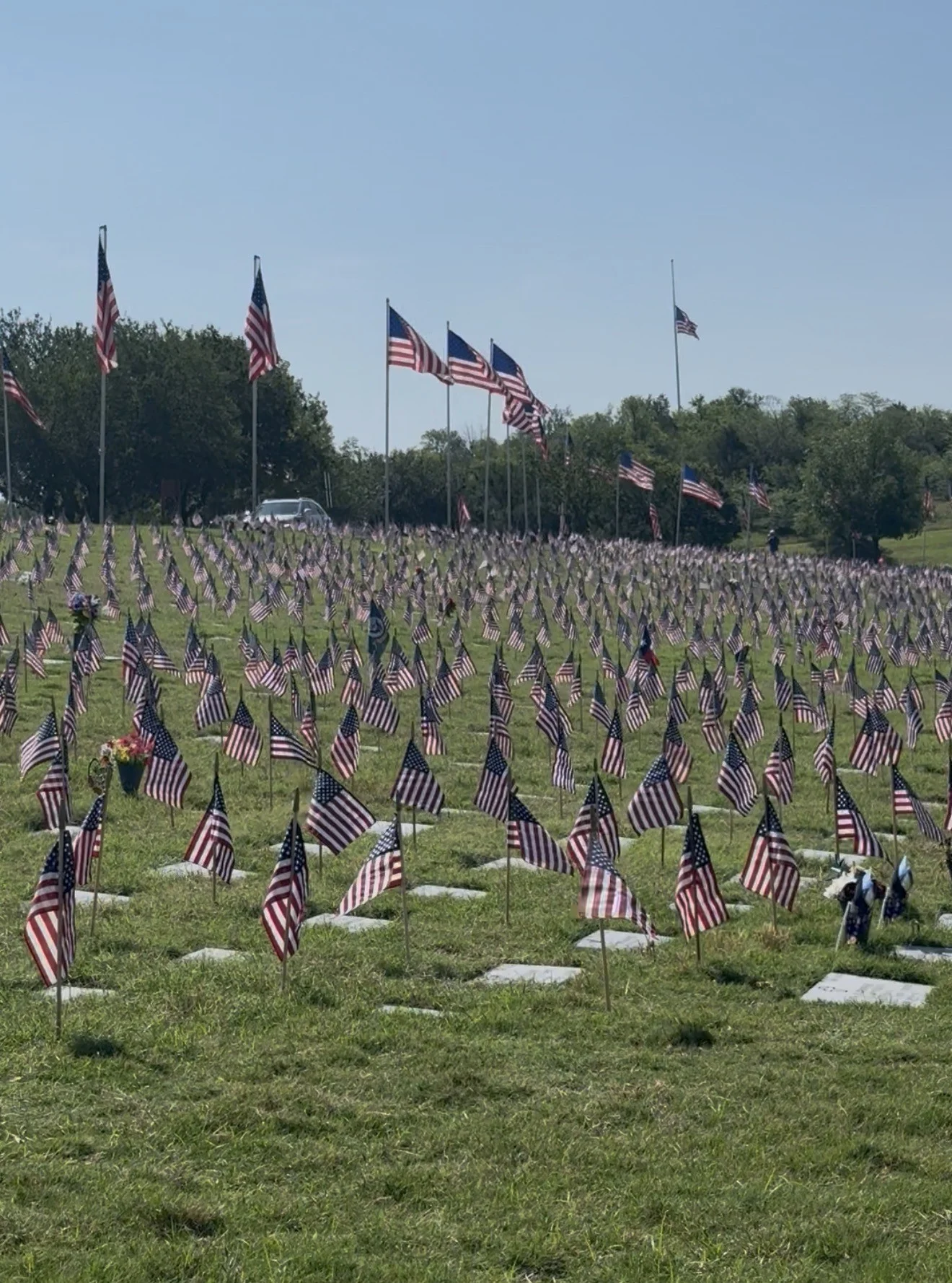 Volunteers placing American flags on grave markers for Memorial Day